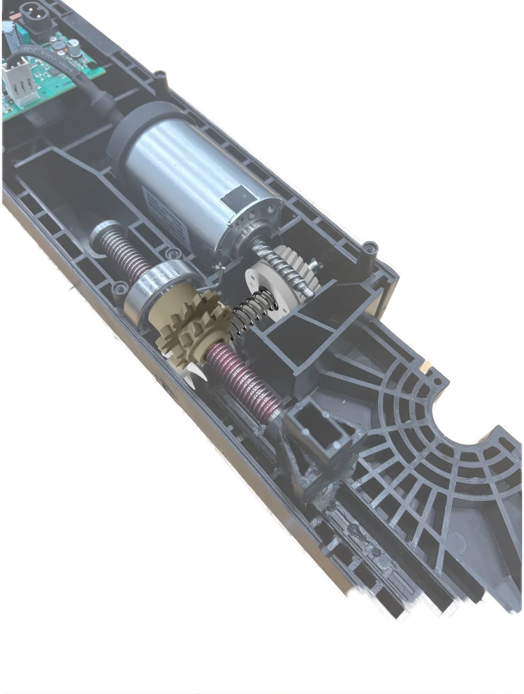 Photo of the opened TWINDRIVE actuator: the silver motor, the worm, the beige gear nut and the long threaded spindle inside the black housing.