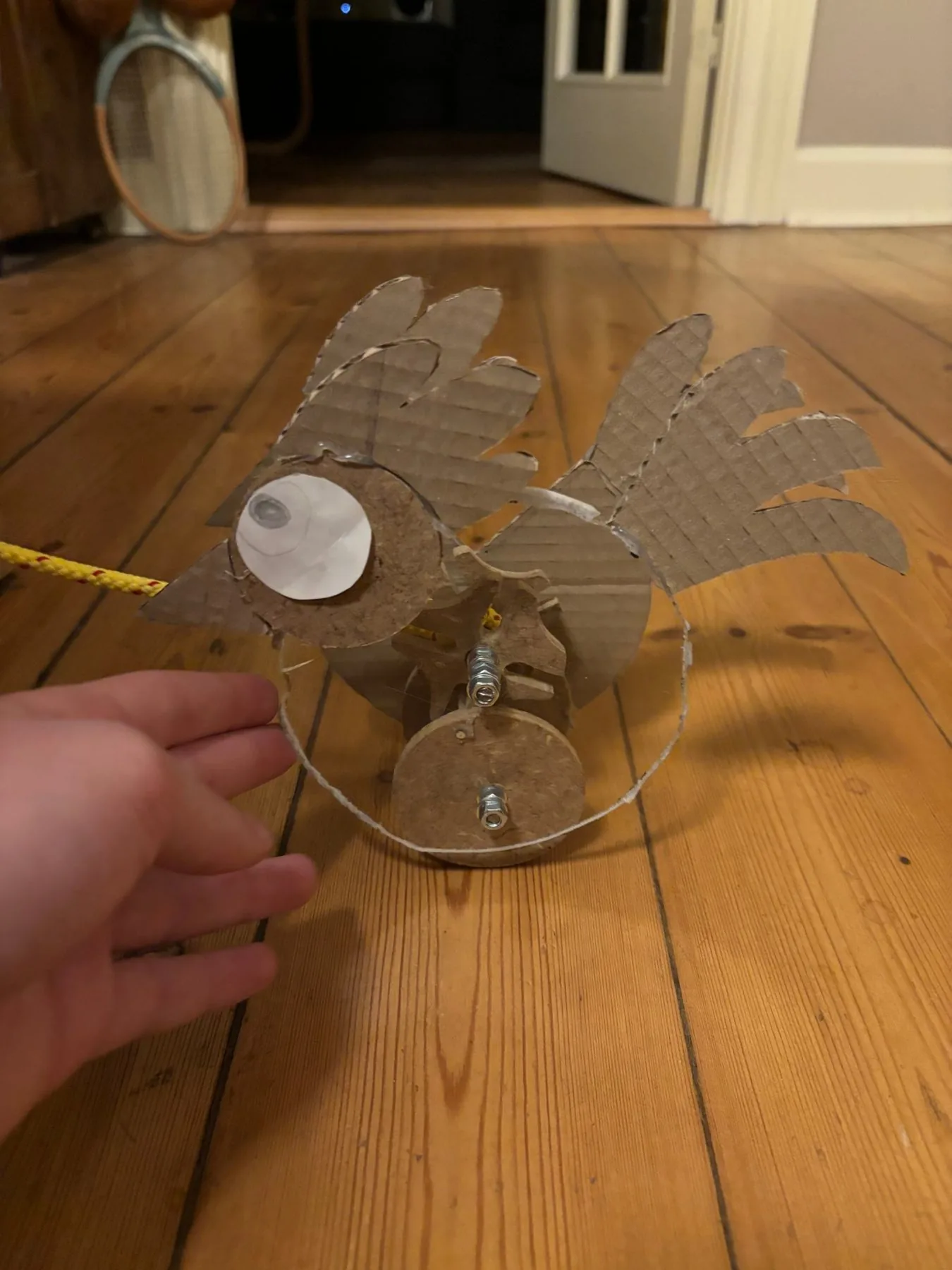 The prototype on the floor seen from the front, pull rope attached at the beak